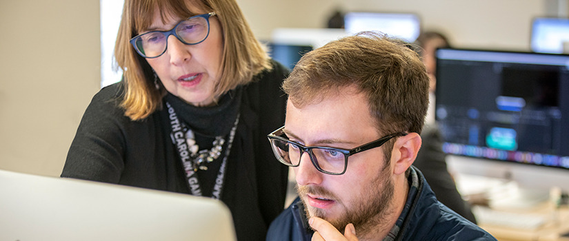 Banner Image with two faculty looking at computer screen