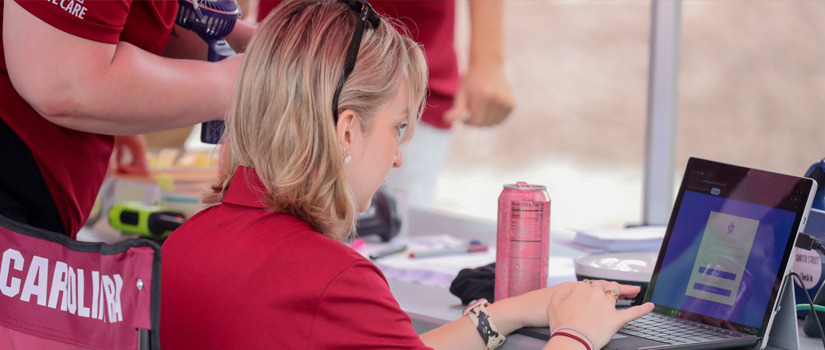 A student in a garnet polo types on her laptop signing in to the housing portal