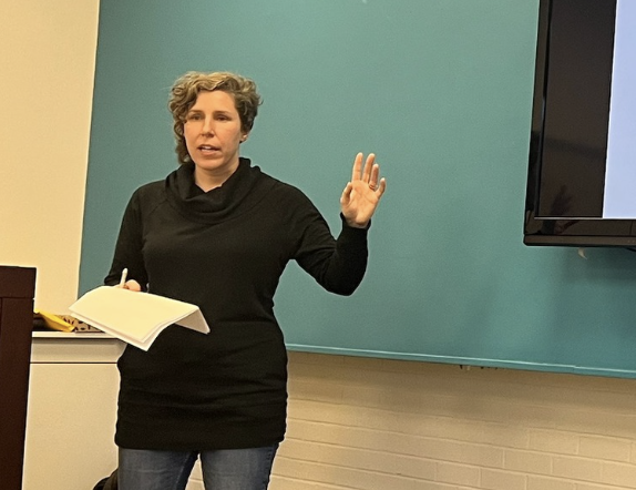 Lisa Cantrell, a white woman with a short, cropped hair cut, gestures while instructing the elevator pitch workshop.