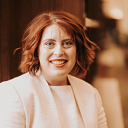 photo of a woman in a white suit smiling 