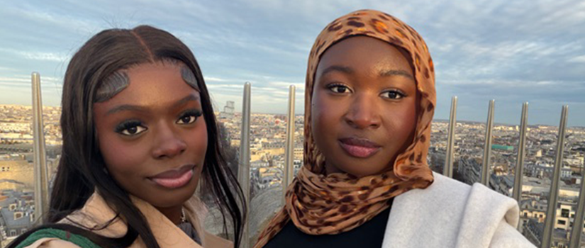 Two students pose together on an observation deck overlooking a city skyline.