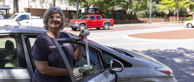 Kirstin Dow stands by a car and shows a temperature sensor fitted over the passenger side window.