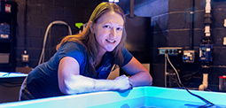 A woman leaning over an aquatic research pool, observing the water and marine life