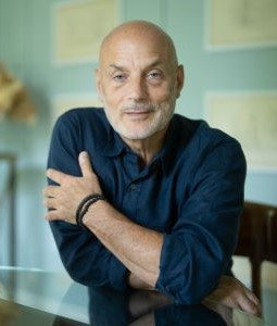 a man with a dark blue shirt leaning over a chair