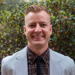 man smiling with gray blazer on with a blue shirt