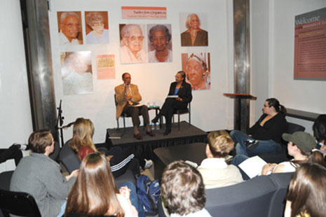 two people sitting on a dais. a small group of others are around them in chairs.