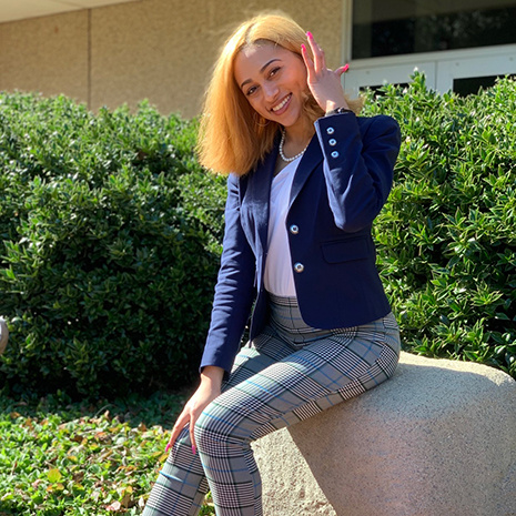 Alexis Lewis sits on a rock.