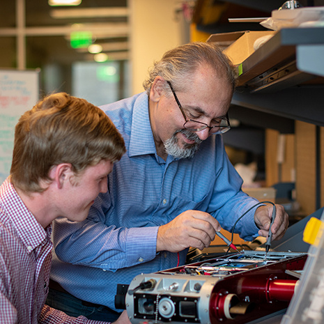 Dr. Rekleitis and a student work on a small robot together