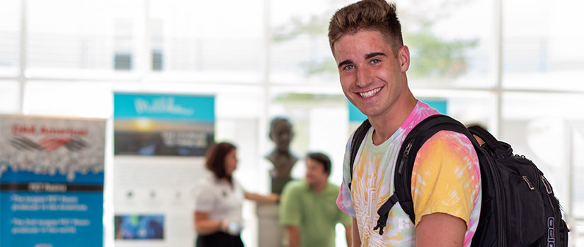 student with backpack smiles in lobby