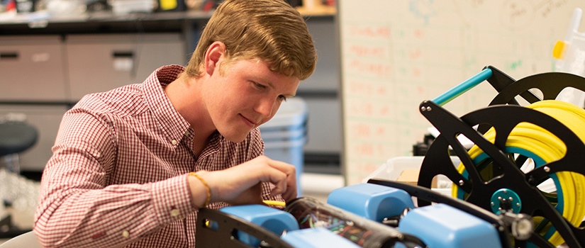 male student works on a robot