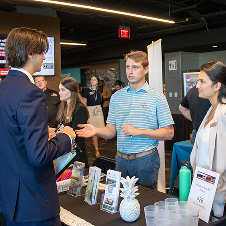 Two recruiters speak with an HRSM student at the Experience Expo.