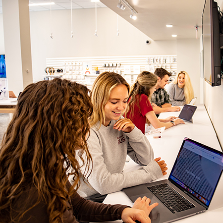 Students look at laptops while speaking with sales reps at the Gamecock's iHub store.