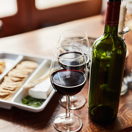 Two wine glasses and a bottle with appetizers