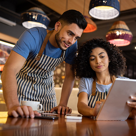 Team of waiters working at a restaurant and looking at the menu on a tablet.