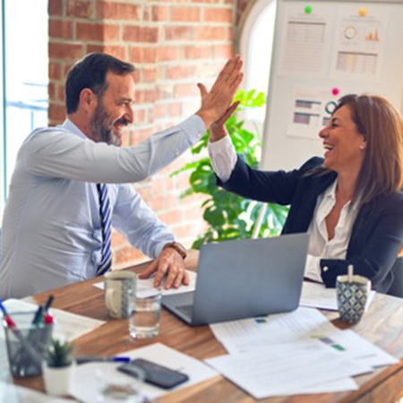 Two people give a high five while sitting at a table.