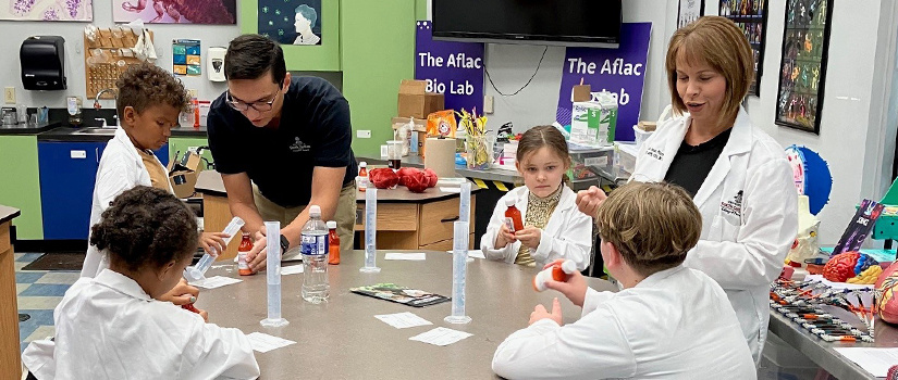 Pharmacy faculty and students with children in EdVenture science lab