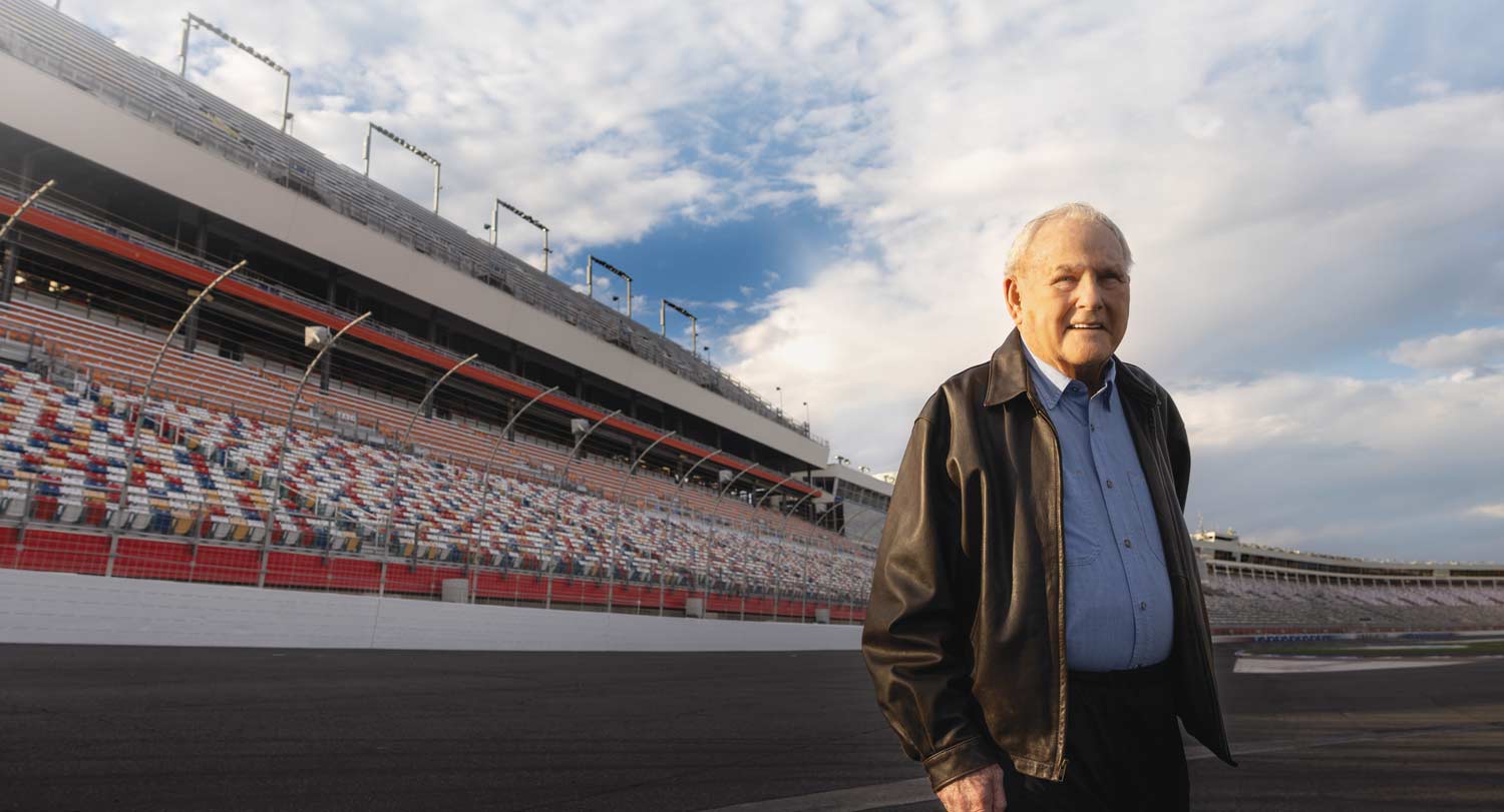 A portrait of Humpy Wheeler with the Charlotte Motor Speedway in the background.