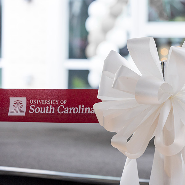 University of South Carolina garnet ribbon stretches across opening and ends in white bow during a ribbon cutting ceremony