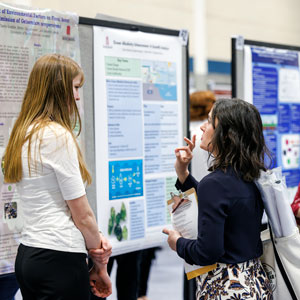 two women talk while looking at posters