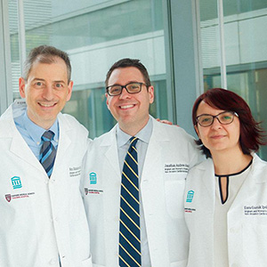 Three doctors standing in the glass hallway of a clinic