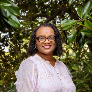 Angela McLeod smiles against a backdrop of greenery. 