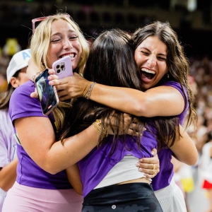 Three women hug excitedly during 2025 sorority bid day at USC