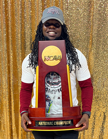 Jonathan Hampton holding the Women's Basketball NCAA Championship trophy.